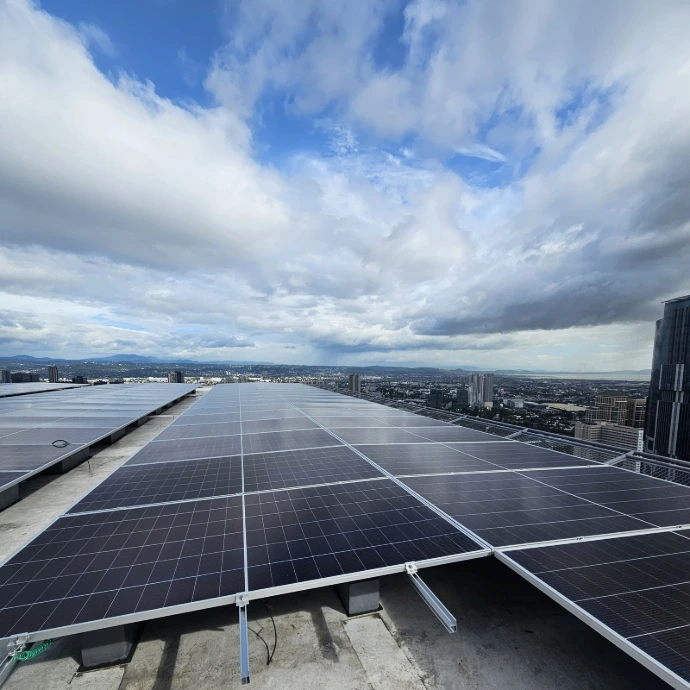 Rooftop solar array on a high-rise building against a blue sky, Metro Manila