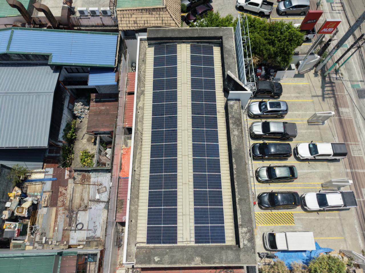 Aerial view of a commercial rooftop solar array beside a parking area, Metro Manila