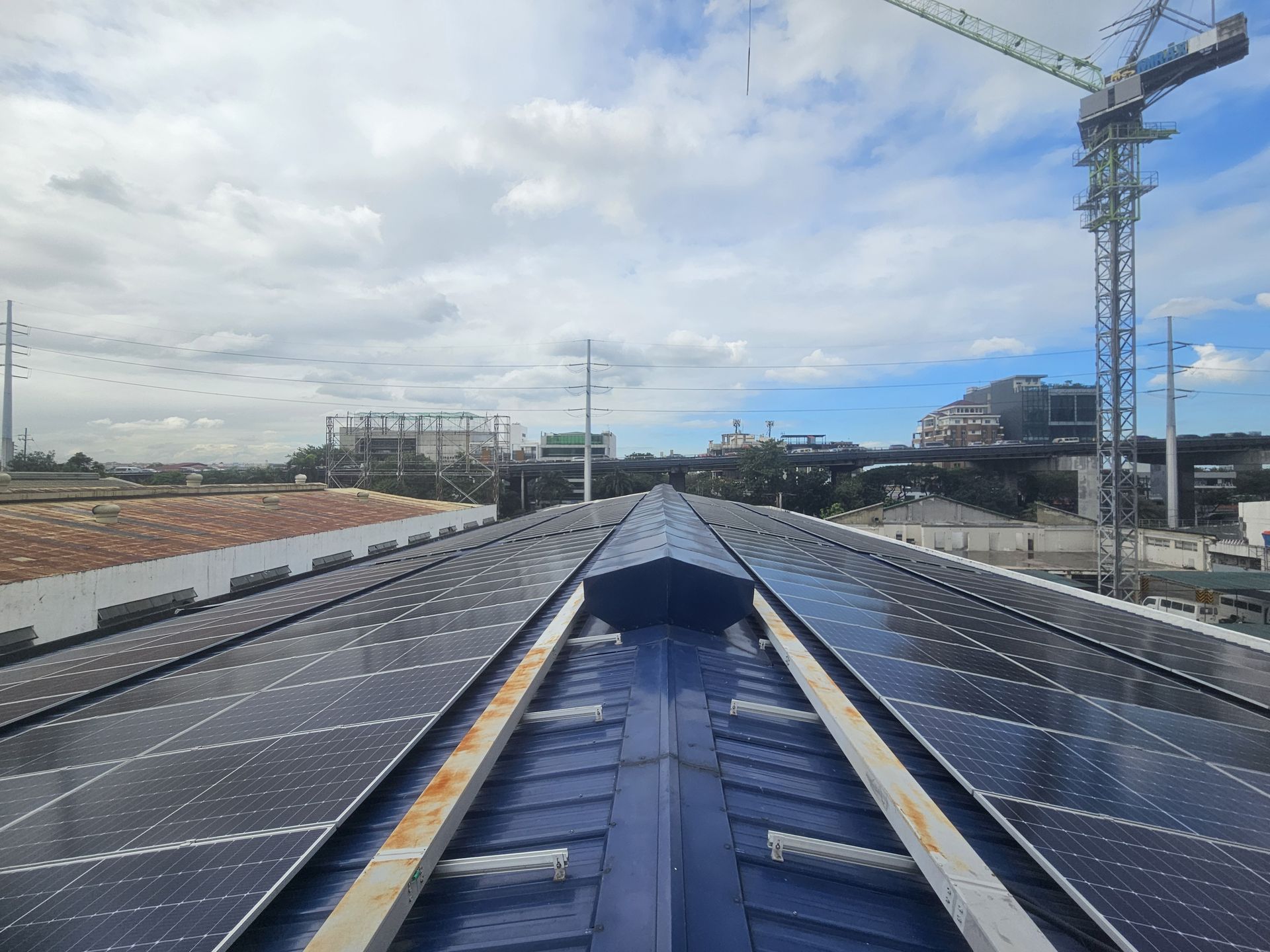 Long rooftop solar array on a commercial building with the Metro Manila skyline behind
