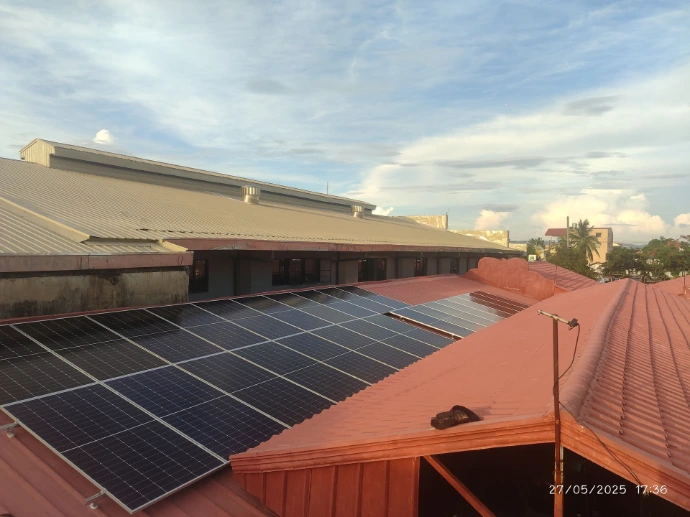 Solar array installed on a red metal roof with the Metro Manila skyline behind