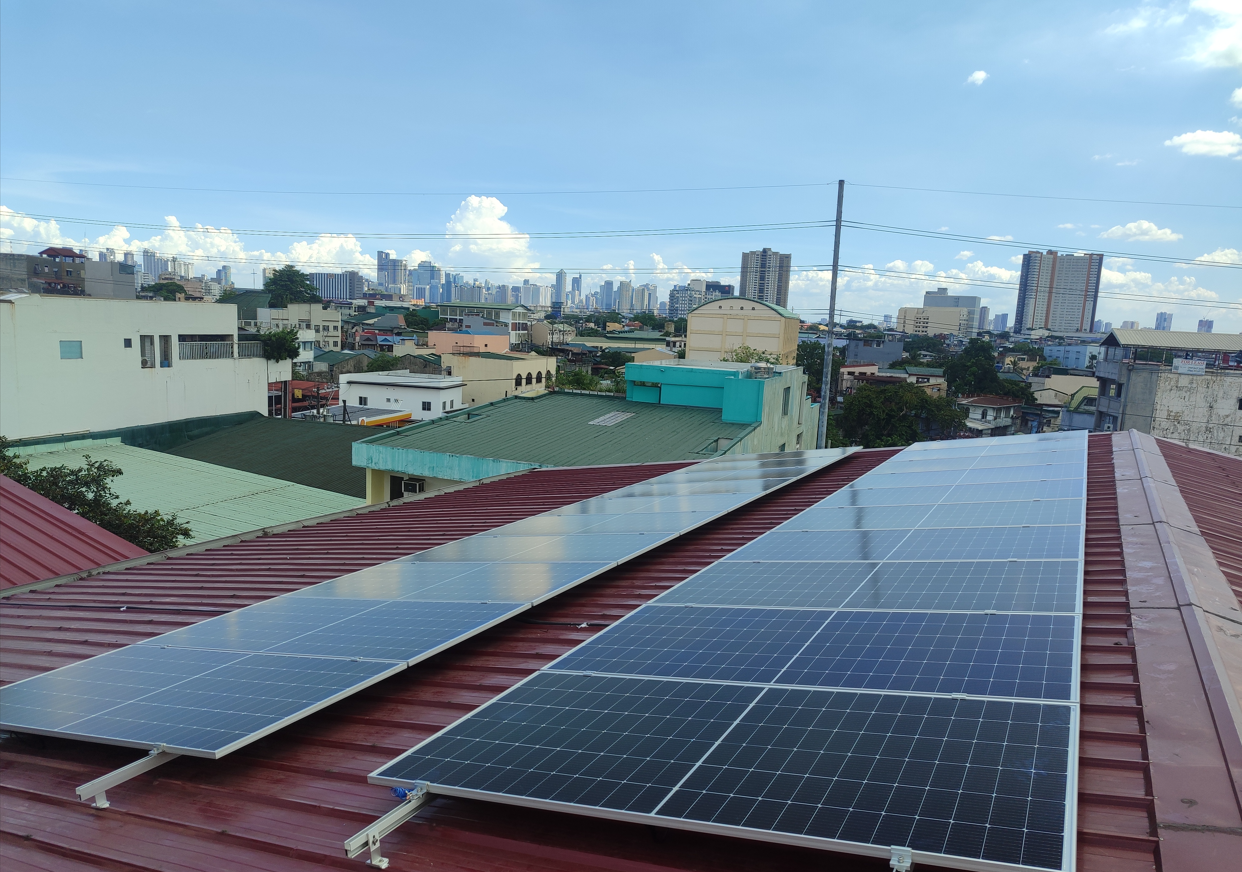 Rooftop solar array on a commercial building with the Metro Manila skyline behind