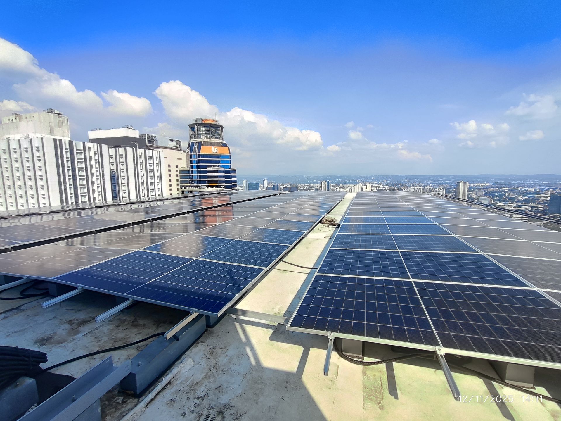 Rooftop solar array on a commercial building with the Metro Manila skyline behind